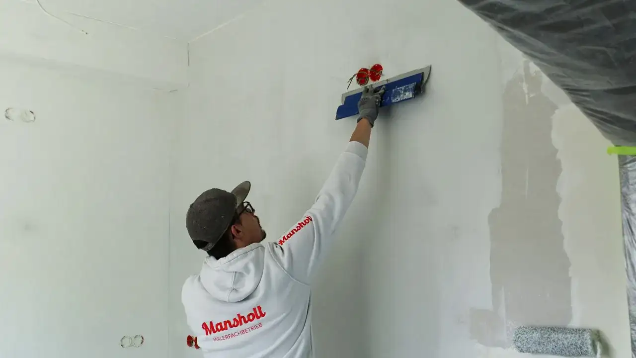Maler spachtelt Rigips-Wand glatt für ein makelloses Finish.