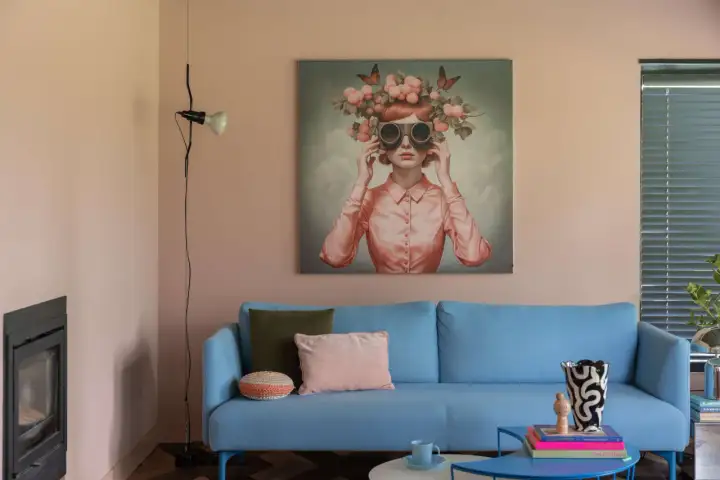 Ein hellblaues Sofa mit Kissen vor einem rosa Wandbild. Tolle wohnung einrichten ideen mit einem auffälligen Kunstwerk.